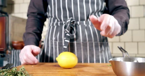 Close-up of an unrecognizable male chef in an apron spinning a lemon and Stock Footage 149187736