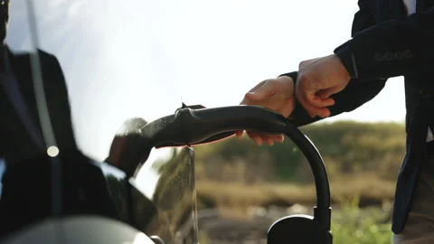 Close up of unrecognizable male hand inserts power connector into EV car uses Stock Footage 220295502