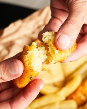 Close-up of unrecognizable man breaking a stuffed potato with his hand. Tradi Stock Photos
