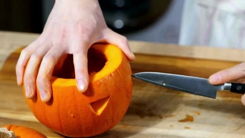 Close-up of an unrecognizable man carving a pumpkin for Halloween lighting an Stock Footage 272459844
