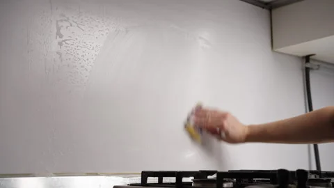 Close-up of unrecognizable man cleaning kitchen wall with soapy sponge, removing Stock Footage 305999872