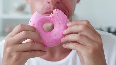 Close-up of an unrecognizable man eating a donut in pink icing Stock Footage 175165602