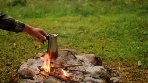 Close up of unrecognizable man make coffee on campfire at beautiful summer day Stock Footage 247135039