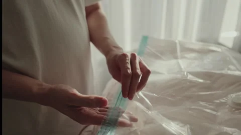 Close-up of unrecognizable man opening vacuum compression bag for stacking Stock Footage 304881653