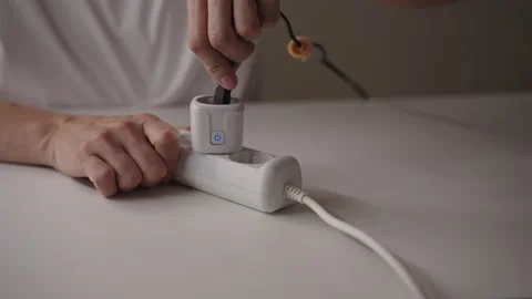 Close-up of unrecognizable man plugging smart plug into white extension cord on Stock Footage 317303078