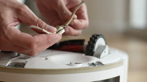 Close-up of unrecognizable man removing spinning brush from robot vacuum cleaner Stock Footage 251583770