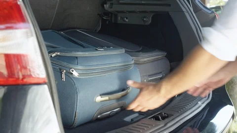 CLOSE UP: Unrecognizable man unloading heavy suitcases from modern black SUV. Stock Footage 90479880