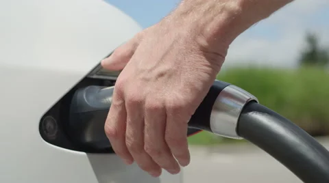 CLOSE UP: Unrecognizable man unplugging car from electricity grid on sunny day Stock Footage 67306555