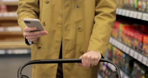 Close up of unrecognizable man using smartphone while carrying shopping cart Stock Footage 189813585