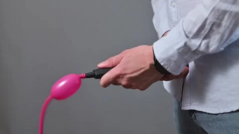 Close-up of an unrecognizable person trying unsuccessfully to inflate a balloon Stock Footage 338300200