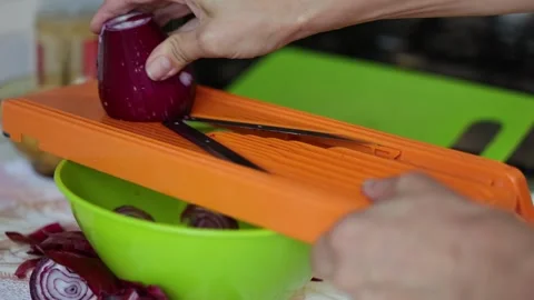 Close up of an unrecognizable person using a mandoline slicer to cut an onion Stock Footage 345740915