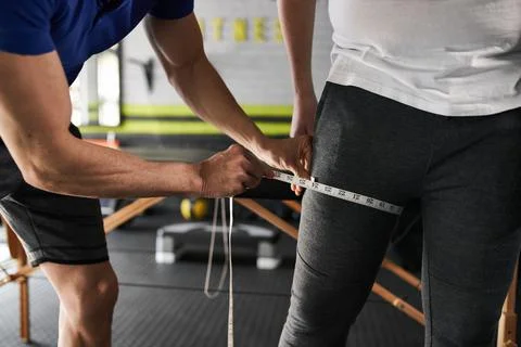 Close up unrecognizable personal trainer measuring thigh Stock Photos
