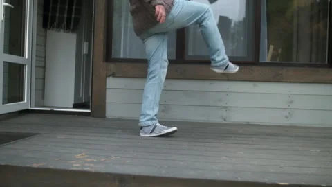 Close-up, unrecognizable rude customer kicks a cardboard box from his porch at Stock Footage 223894621