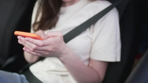 Close-up - unrecognizable woman writes a message buckled up behind the wheel Video stock 181933211