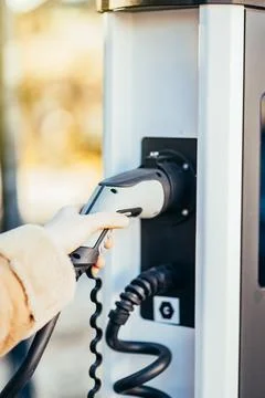 Close-up of an unrecognizable woman's hand holding an electric car charger Stock Photos