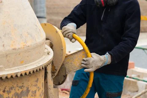 Close up of unrecognizable worker using a yellow concrete mixer machine Stock Photos
