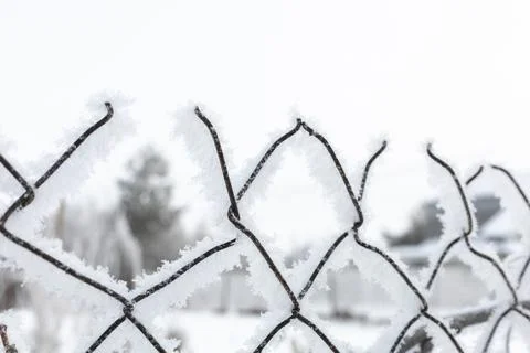 Close-up of upper part of old net slightly covered with snow surrounding some Stock Photos