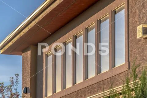 Close up of upper storey of home with rectangular windows lining the ...