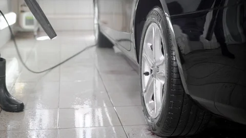 Close ups shot of a man using high pressure water jet to wash car in a carwash. Stock Footage 91195995