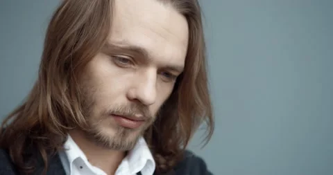 Close up of upset face of young handsome caucasian man with long hair in suit Stock Footage 147050959