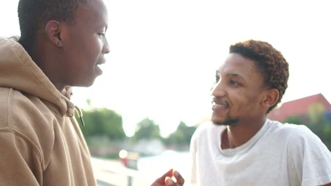 Close urban outside portrait of two African American guys talking and smiling at Stock Footage 137050823