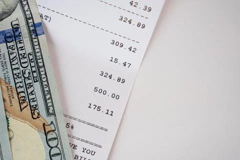 Close-up of US dollar bills and printed receipt on light background. Stock Photos