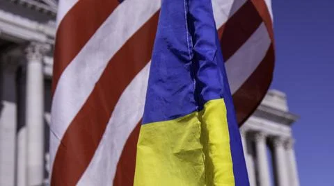 Close up of US, Ukraine flags overlapping with capitol building in background 库存照片