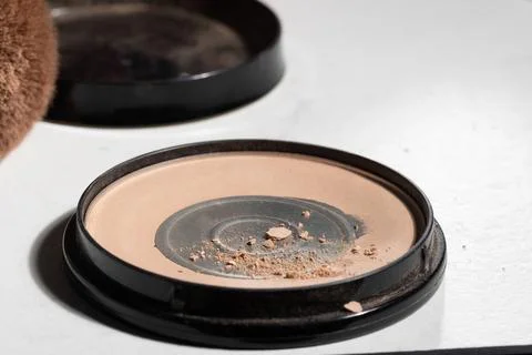 Close-up of a used makeup compact with crushed powder and exposed pan on a wh Stock Photos
