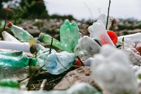 Close up of used plastic bottles on stone beach. Plastic pollution. Environ.. Stock Photos