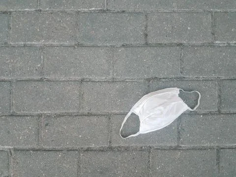 Close up. used protective mask on the sidewalk Stock Photos