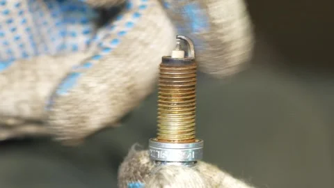 Close-up of used spark plug held by blue-textured work gloves Stock Footage 347903072