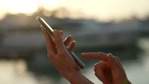 Close-up of using a mobile phone to send a message in the setting sun in the 動画素材 158277250