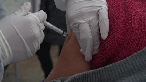 Close-up vaccinating an elderly woman's man against covid-19 with mask and Stock Footage 156307191