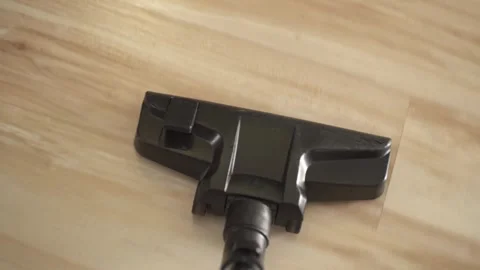 A close-up of a vacuum cleaner brush that cleans a light wooden laminate floor Stock Footage 277873904