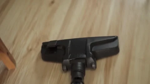 A close-up of a vacuum cleaner brush that cleans a light wooden laminate floor Stock Footage 277873990