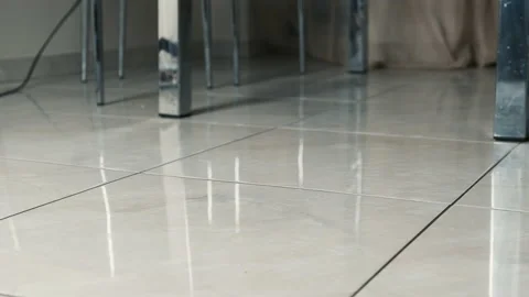 Close-up of a vacuum cleaner that removes dust on the tiles under the table Stock Footage 150054897