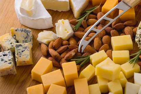 Close-up of various cheese with almonds and knife on wooden board, copy space Stock Photos