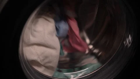 Close-up of various clothes spinning inside washing machine drum during washing Stock Footage 294107048