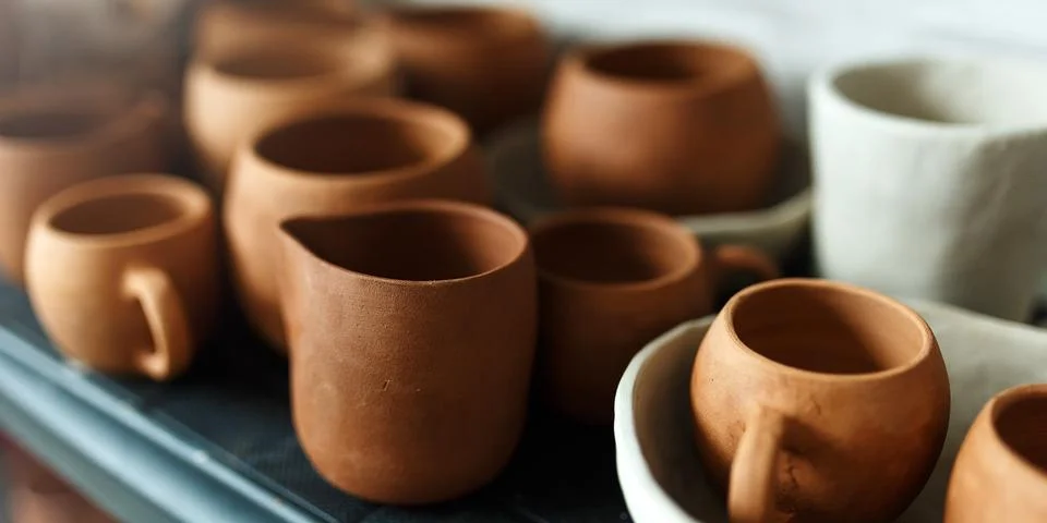 A close-up of various drying clay tableware on a shelf. A pottery studio concept Stock Photos