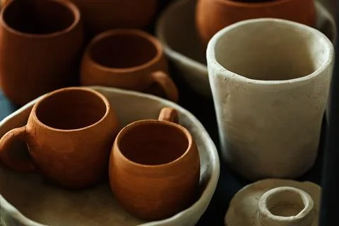 A close-up of various drying clay tableware on a shelf. A pottery studio concept Foto stock