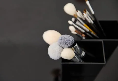 Close-up of various makeup brushes in holders against a dark background Stock Photos