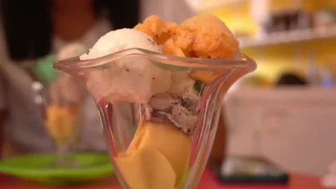 Close-up of various orange, yellow and white ice cream balls in a glass cup at d Stock Footage 196728535