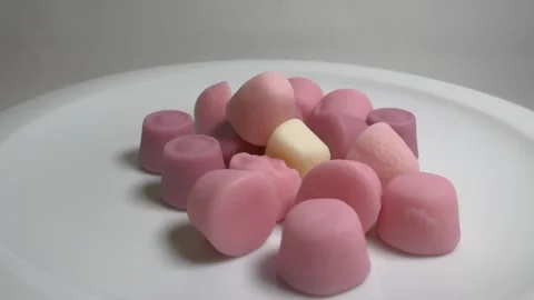 Close-up of various pink and cream-colored gummy candies on a white plate, .. Stock Footage 331354103