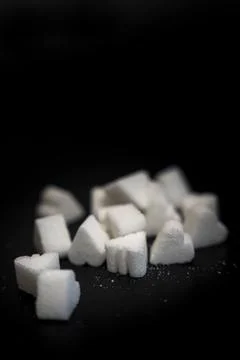 Close-up of various shapes of sugar cubes arranged against a dark background. Stock Photos