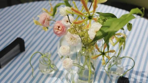 Close-up of vases with flowers on a table in a cafe on a blue tablecloth. Table Stock Footage 318064931