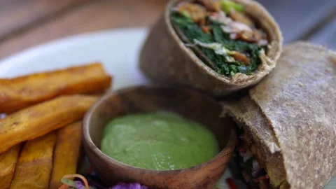 Close up of vegan wrap served with a sauce, coleslaw and sweet potatoes on a Stock Footage 146048317