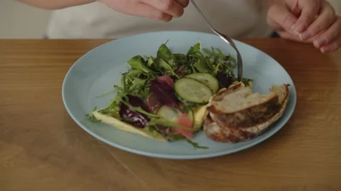 Close-up of vegetable salad and slices of bread. The woman sits down at the Stock Footage 234898657
