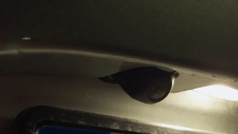 Close-up of vehicle rearview camera mounted under bumper with bright light and Stock Footage 338134185