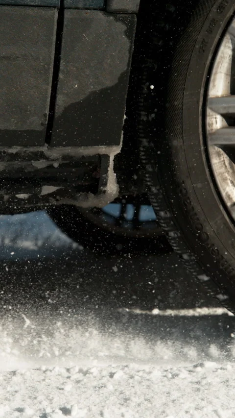CLOSE UP: Vehicle's wheels throw up pieces of snow while gaining traction. Video stock 315801662