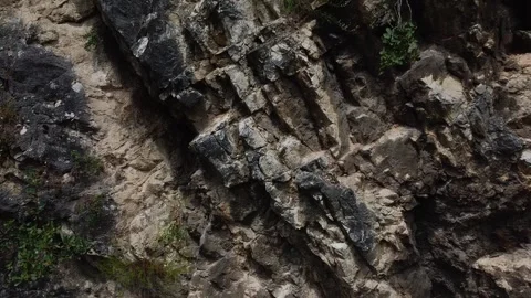 Close-Up Vertical Ascent Revealing Massive Craggy Rock Face Texture Stock Footage 319995759